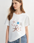 Woman wearing a white t-shirt with starfish designs on a plain background