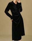 Black velvet dress worn by a model on a beige background