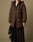 Person wearing a brown puffer coat against a beige background