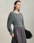 Woman wearing a gray sweater and skirt with 'Amii' brand logo.