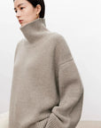 Woman wearing a beige turtleneck sweater against a plain background
