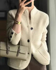 Person wearing a cream-colored cardigan holding a matching handbag.