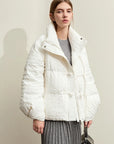 Person wearing a white quilted jacket against a plain background