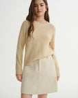 Woman wearing a beige sweater and skirt on a white background