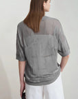 Person wearing a gray mesh top with a plain background, featuring the brand 'Amii'.