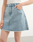 Light blue denim skirt worn by a person on a white background
