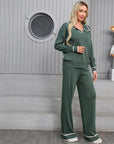 Woman wearing a green pajama set standing in front of a gray wall with a decorative robot figure.