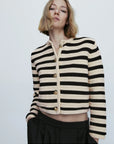 Woman wearing a black and white striped cardigan on a light gray background