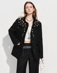 Woman wearing a black textured jacket with colorful embellishments on a white background, featuring the brand 'fsle'.