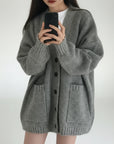 Person wearing a gray cardigan taking a mirror selfie.