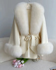 White fur coat with pom-pom details on a white surface