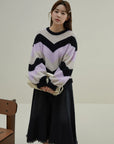 Woman wearing a colorful sweater and black skirt in a minimalistic setting
