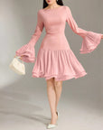 Pink dress with flared sleeves on a model against a neutral background