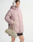 Person wearing a pink puffer jacket and white ear muffs on a white background