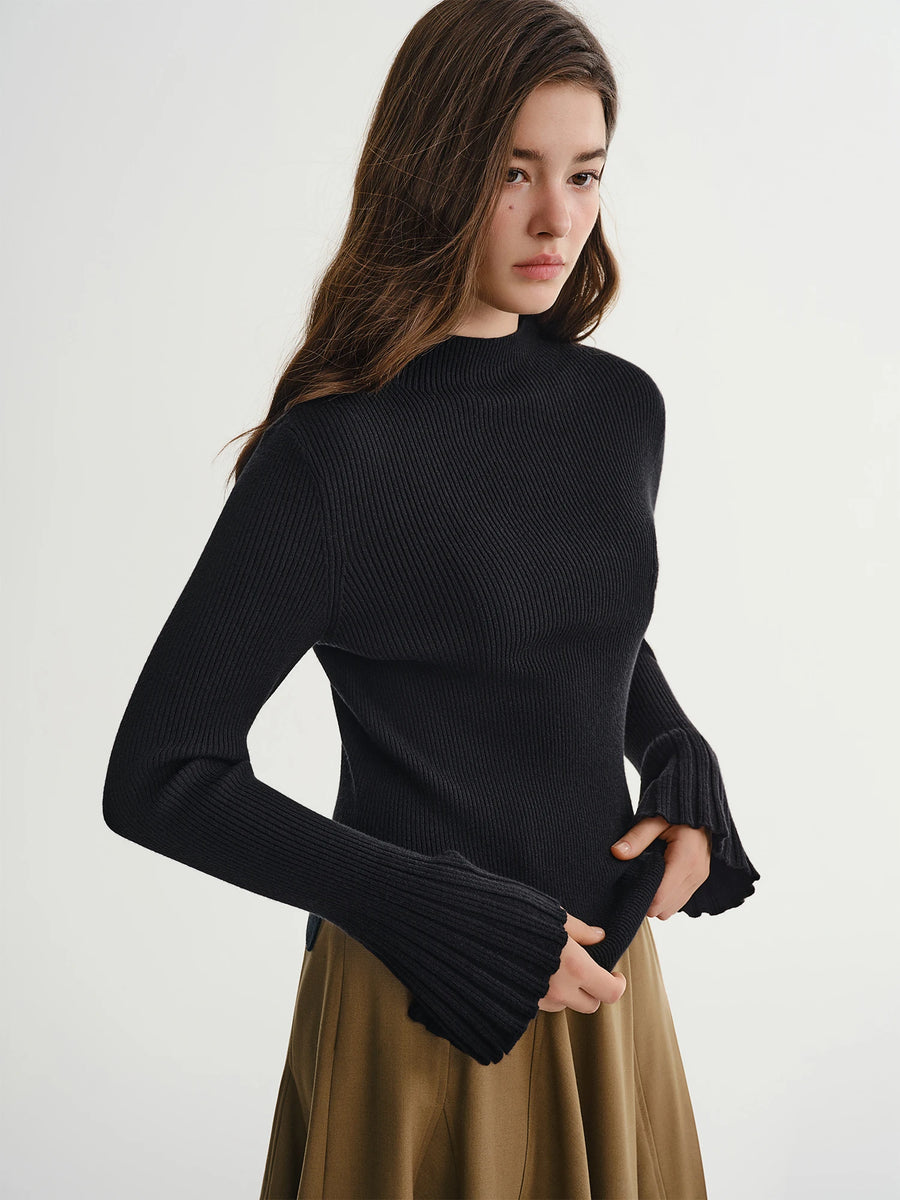 Woman wearing a black ribbed sweater and beige skirt on a white background