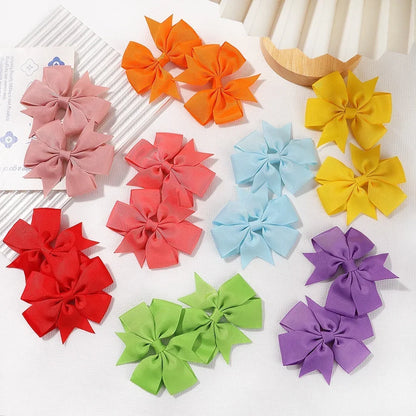 Colorful hair bows arranged on a white surface with a wooden bowl in the background.