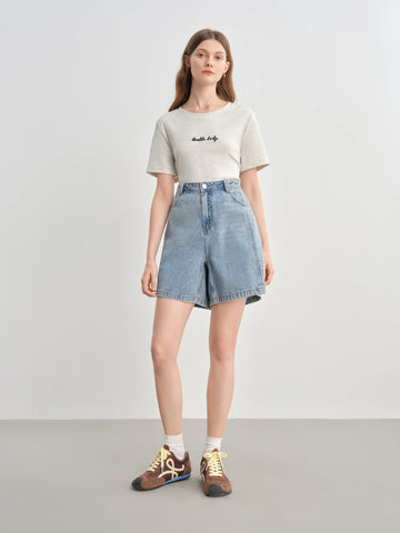 Woman wearing a white t-shirt and denim skirt on a plain background