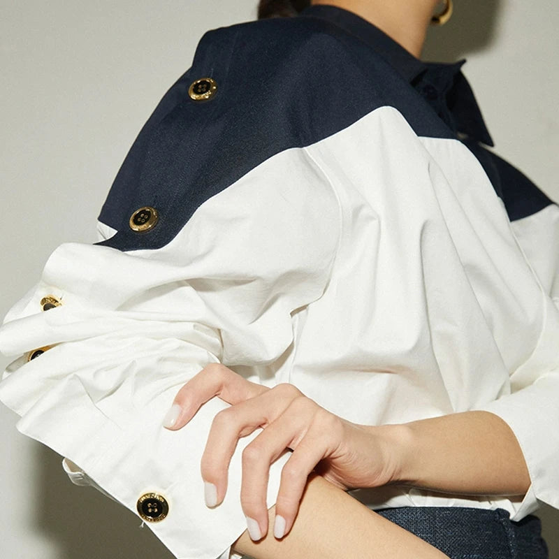 Close-up of a person wearing a navy and white jacket with gold buttons.