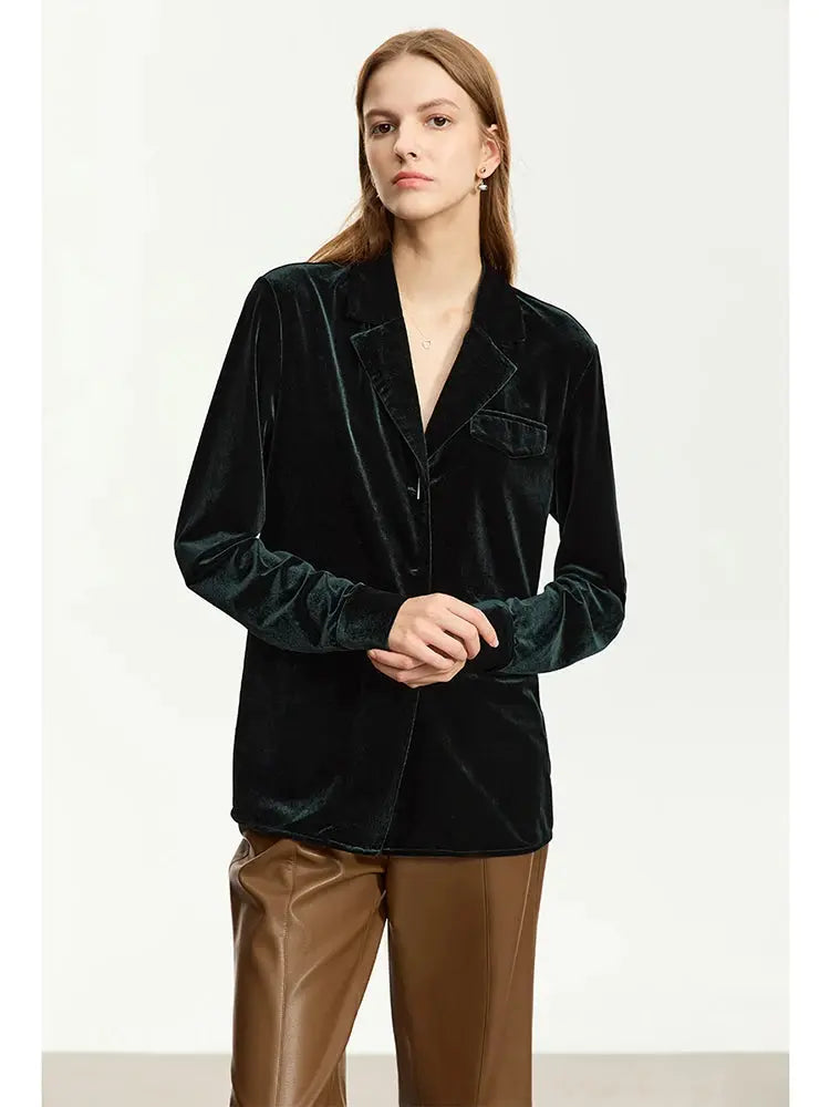 Woman wearing a black velvet blazer and brown pants on a white background