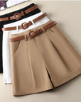 Three pairs of shorts in black, white, and beige with brown belts on a beige background.