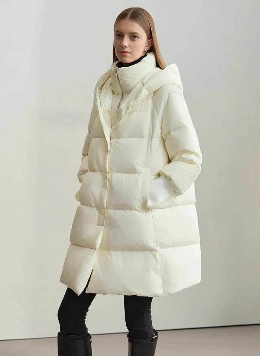 Woman wearing a white puffer coat with a hood on a plain background, featuring the AMII brand.