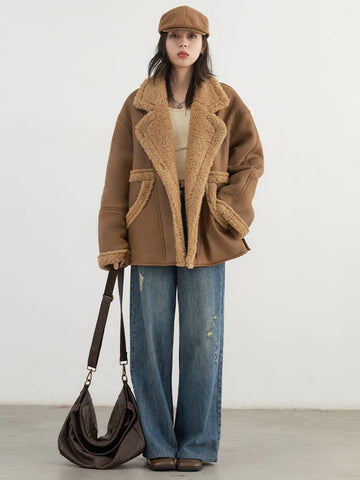 Person wearing a brown shearling coat, holding a brown bag, against a white background