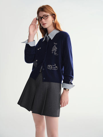 Person wearing a navy cardigan with embroidered designs on a white background