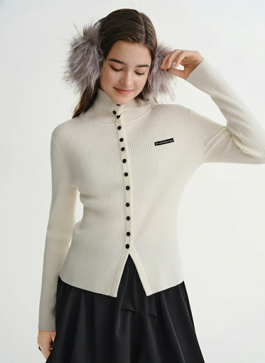 Woman wearing a cream-colored cardigan with black buttons and fur trim, standing against a white background. Brand 'DUSHU' visible.