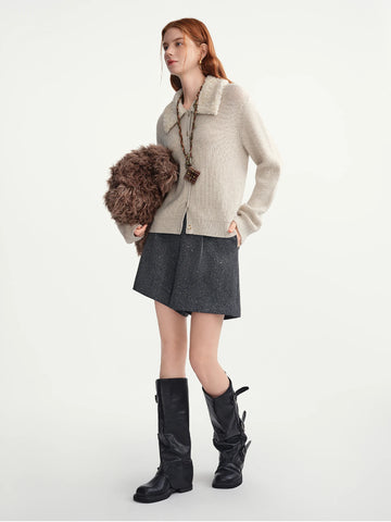 Woman wearing a beige sweater, gray skirt, and black boots on a white background