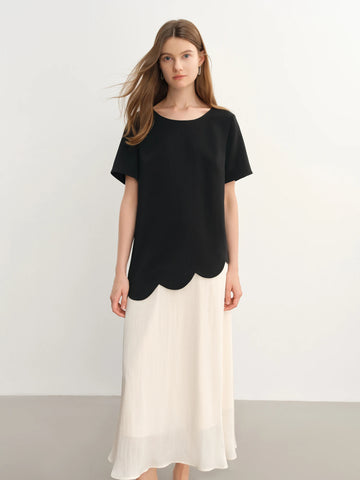 Woman wearing a black top and white skirt on a plain background