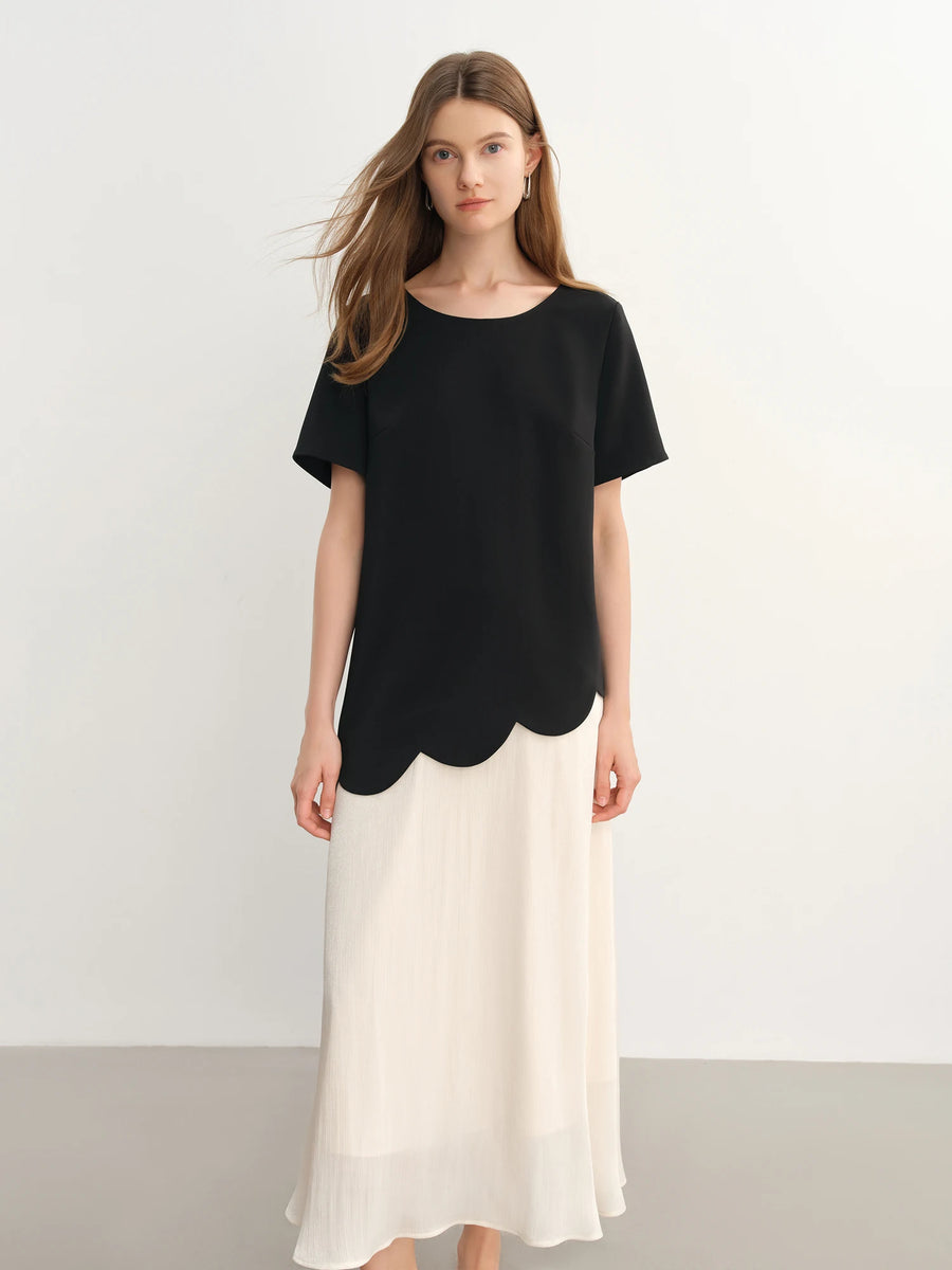 Woman wearing a black top and white skirt on a plain background