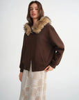 Woman wearing a brown jacket with fur hood on a white background