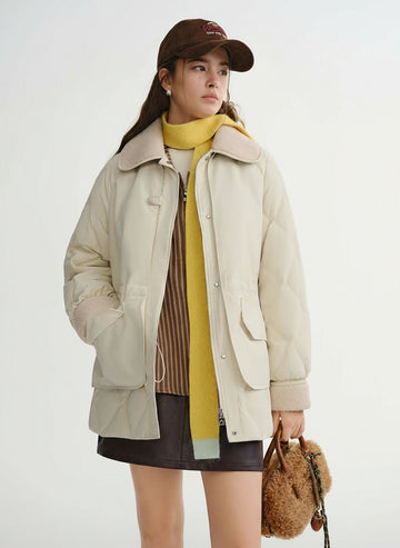 Woman wearing a beige coat, yellow scarf, and brown cap with a white background