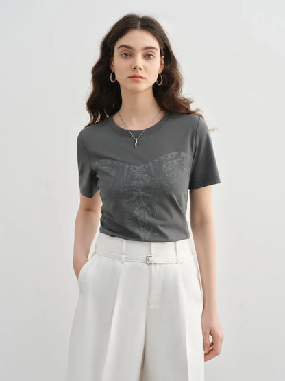 Woman wearing a gray t-shirt with a subtle pattern and white pants on a light gray background