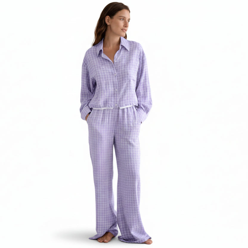 Woman wearing a purple checkered pajama set against a beige background