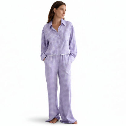 Woman wearing a purple checkered pajama set against a beige background