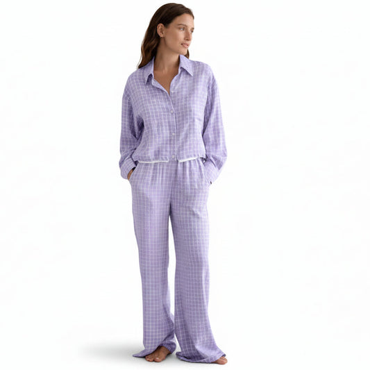 Woman wearing a purple checkered pajama set against a beige background