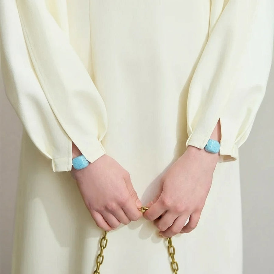 Person wearing a white outfit with blue rings on a plain background, featuring the brand 'Amii'.