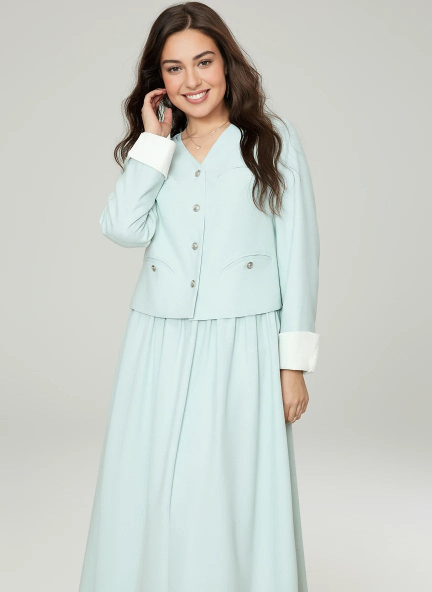 Woman wearing a light blue outfit with a matching jacket and skirt on a pink background