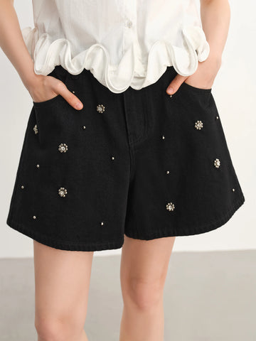 Black shorts with decorative studs worn by a person on a plain background