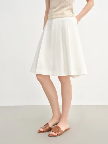 Person wearing a white skirt and beige top on a plain background
