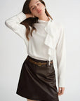 Woman wearing a white blouse and black leather skirt on a light gray background with 'DUSHU' branding.