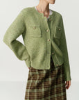 Green knitted cardigan worn by a person on a beige background