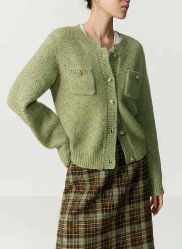 Green knitted cardigan worn by a person on a beige background