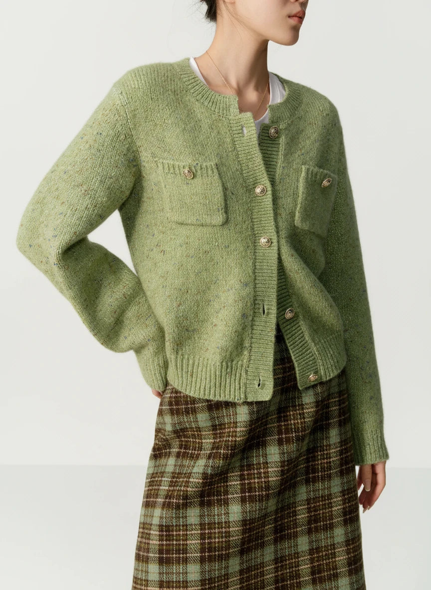 Green knitted cardigan worn by a person on a beige background