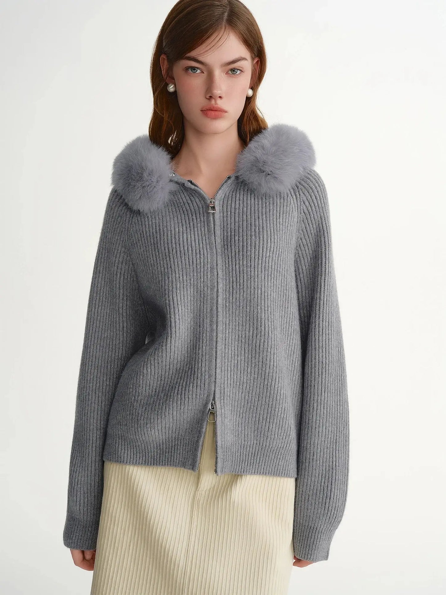 Woman wearing a gray knit cardigan with fur trim on a white background