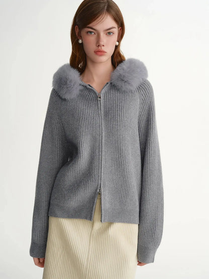 Woman wearing a gray knit cardigan with fur trim on a white background
