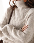 Close-up of a person wearing a beige turtleneck sweater with a blurred background