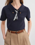 Navy blue shirt with a bow tie and beige pants on a white background
