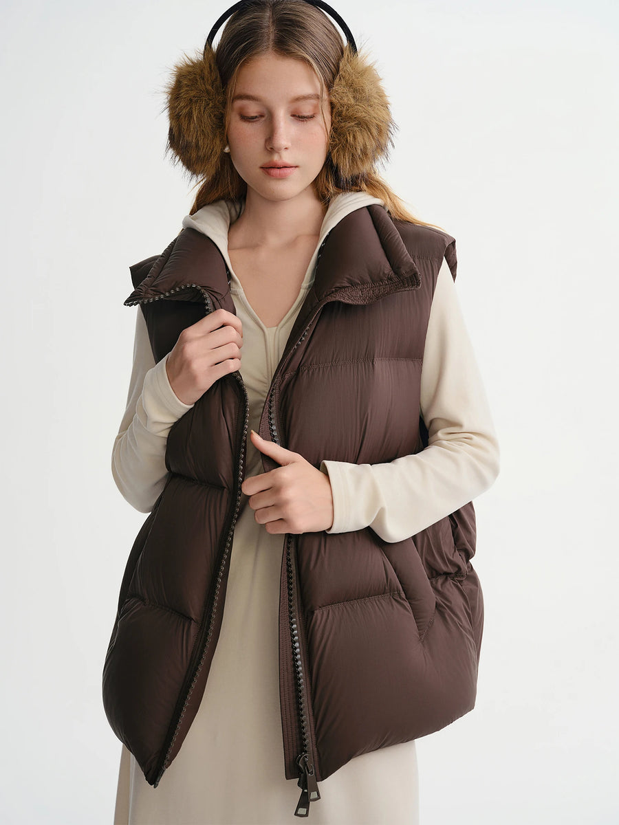 Woman wearing a brown puffer vest and fur ear muffs on a white background